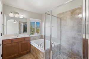 Full bath with vanity, a stall shower, a bath, and light tile patterned flooring