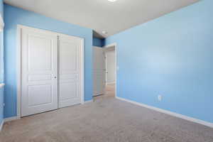 Unfurnished bedroom featuring a closet and light carpet