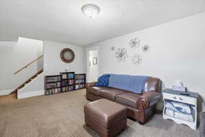 Living area with carpet flooring and a textured ceiling