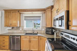 Kitchen featuring stainless steel appliances, light stone countertops, and tasteful backsplash