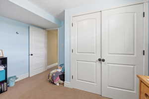 Bedroom with a closet, a textured ceiling, and light colored carpet