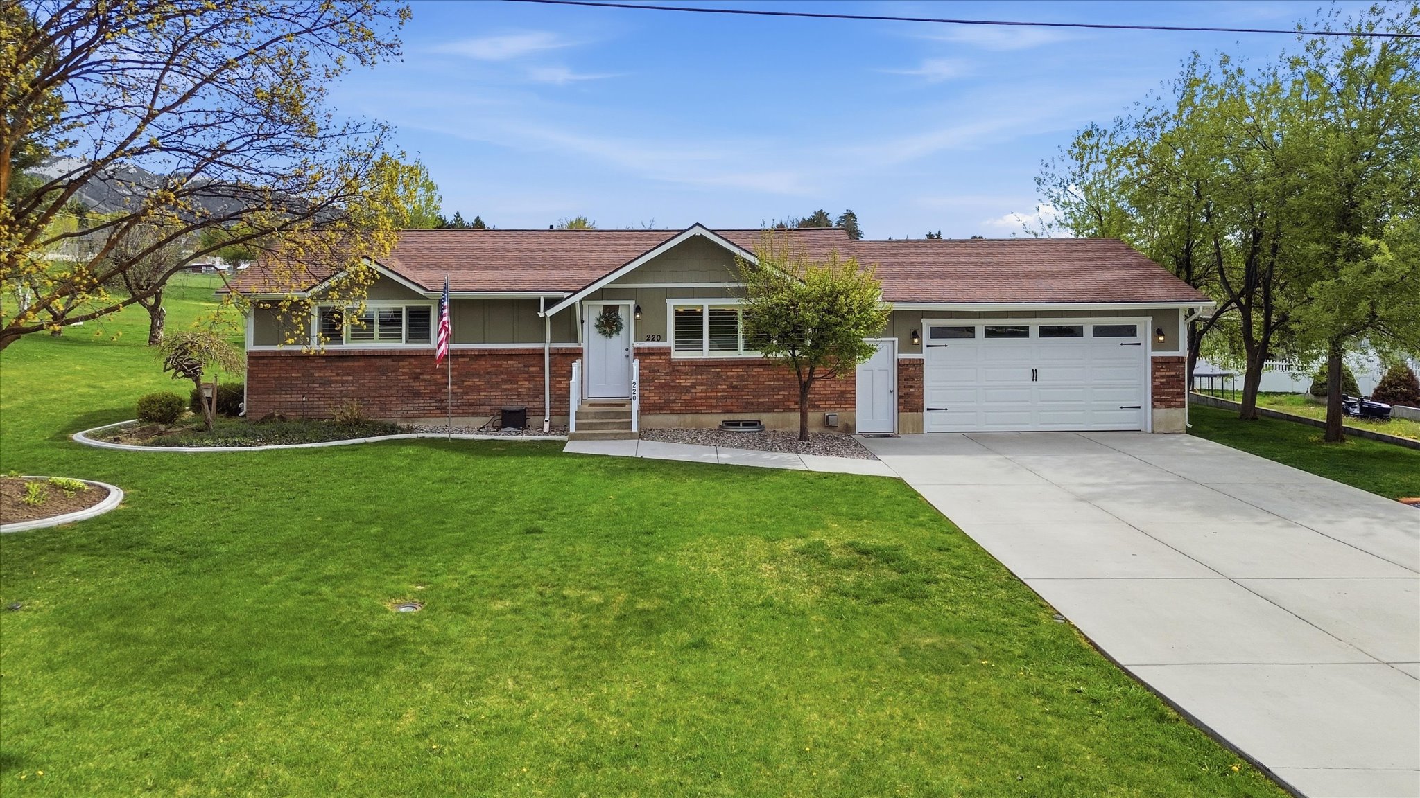 Ranch-style home featuring a front yard, an attached garage, concrete driveway, brick siding, and entry steps