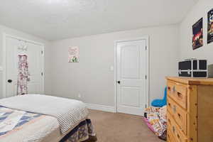Bedroom featuring light colored carpet and a textured ceiling