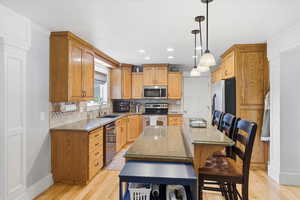 Kitchen featuring dark stone countertops, stainless steel appliances, backsplash, and decorative light fixtures