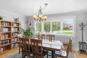 Dining area with light wood-style flooring, suspended lighting, crown molding, and a textured ceiling