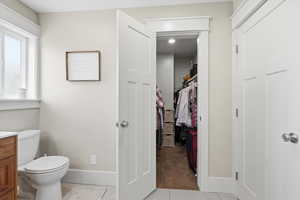 Bathroom featuring vanity, light colored carpet, light tile patterned flooring, and a walk in closet