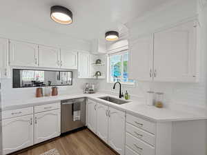 Kitchen featuring white cabinets, dark wood-style flooring, dishwasher, and ornamental molding