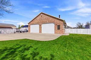 View of side of property featuring brick siding, a gate, a garage, and concrete driveway