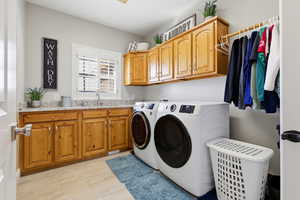 Laundry area with cabinet space, washing machine and dryer, and light wood-style floors