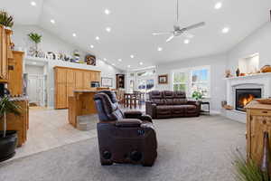 Living area with recessed lighting, light colored carpet, lofted ceiling, a fireplace, and a ceiling fan