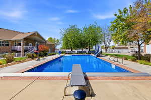 View of pool featuring patio surround, a diving board, and a water slide