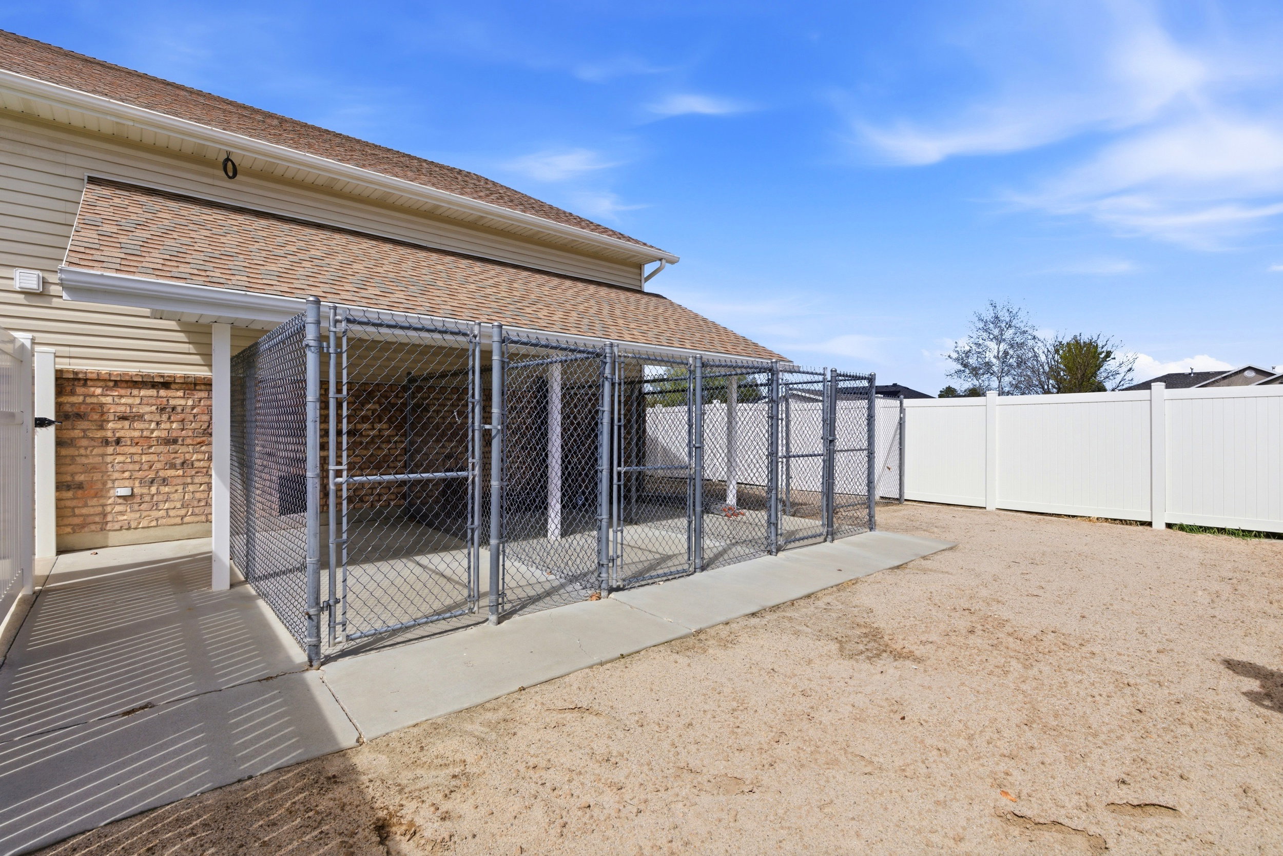 Back of property with an exterior structure, brick siding, an outbuilding, roof with shingles, and a gate