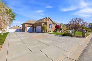 View of front of home with concrete driveway, a garage, a gate, brick siding, and roof with shingles