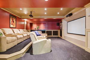 Home theater room featuring carpet floors, recessed lighting, a raised ceiling, and ornamental molding