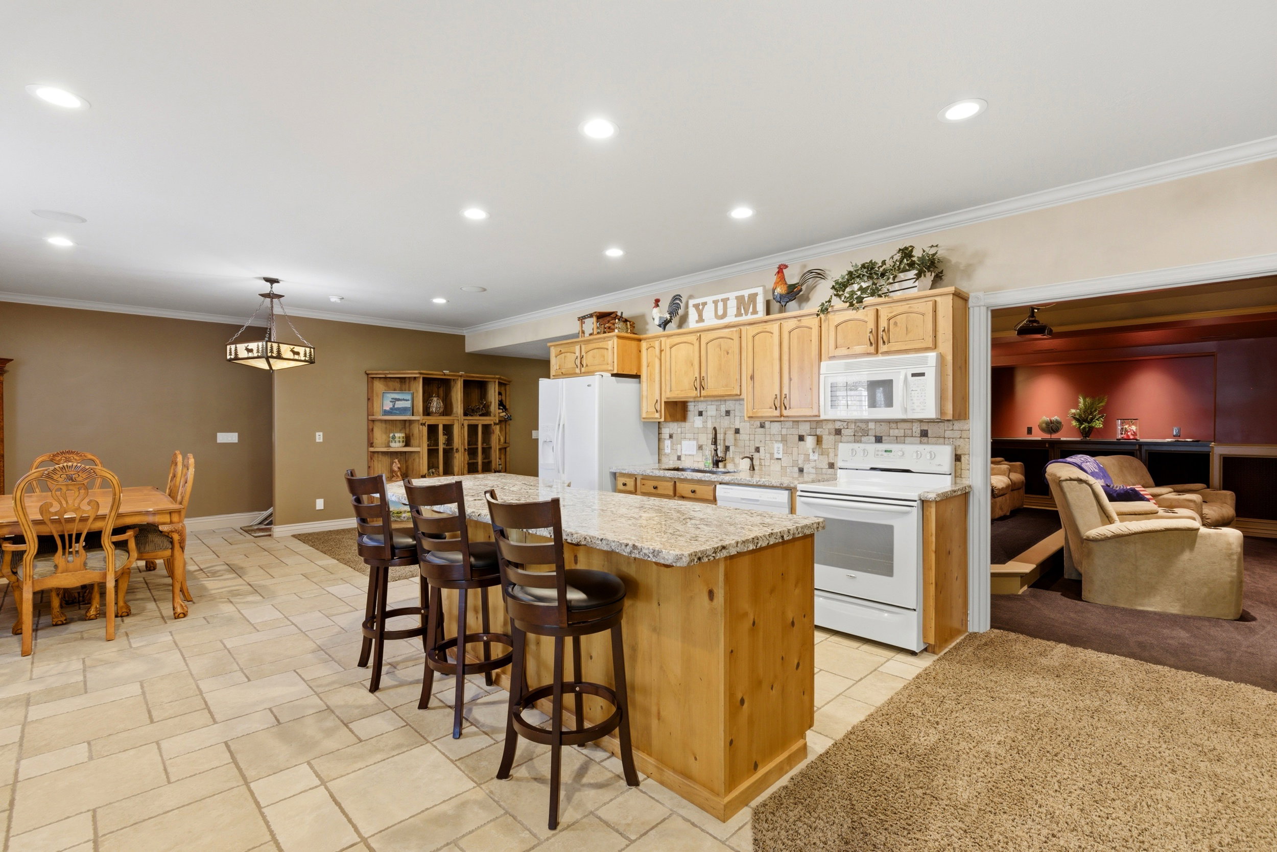 Kitchen featuring open floor plan, white appliances, tasteful backsplash, a kitchen breakfast bar, and a center island