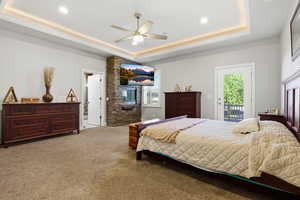 Carpeted bedroom with access to exterior, ceiling fan, and a tray ceiling