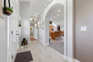 Entrance foyer featuring light wood-style flooring, recessed lighting, arched walkways, and a high ceiling