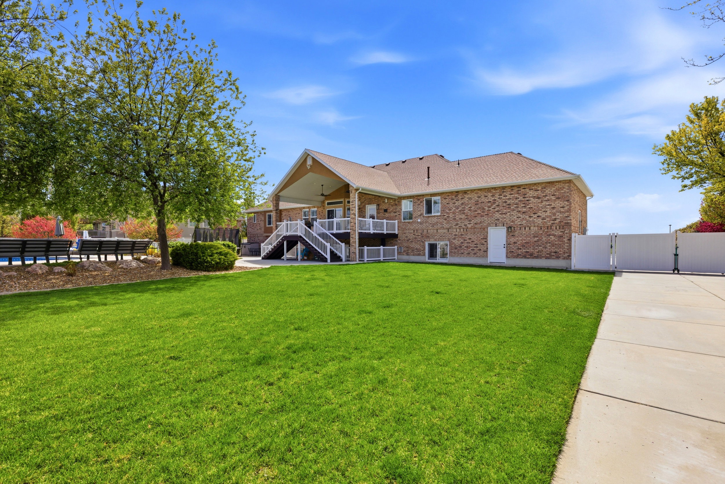 Rear view of property with a gate, brick siding, a patio, and roof with shingles