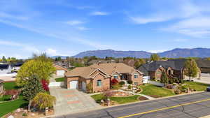 View of front of home featuring a residential view, brick siding, an attached garage, driveway, and a mountain view