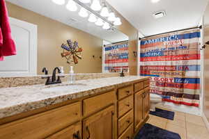Bathroom featuring double vanity, light tile patterned floors, and shower / tub combo with curtain