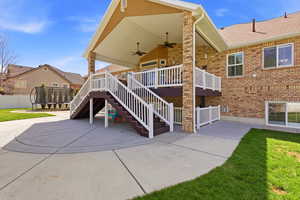 Back of property featuring a trampoline, a ceiling fan, a patio, a wooden deck, and brick siding