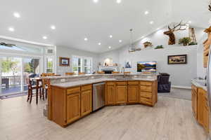 Kitchen with a ceiling fan, a fireplace, open floor plan, wood finish cabinets, and lofted ceiling