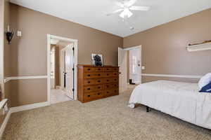 Bedroom featuring light colored carpet, ceiling fan, and connected bathroom