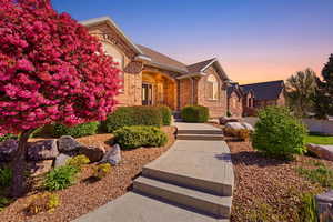 View of front of property featuring brick siding, covered porch, and a shingled roof