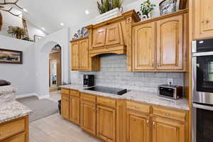 Kitchen featuring stainless steel double oven, light stone countertops, decorative backsplash, recessed lighting, and black electric cooktop