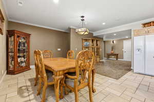 Dining space featuring stone tile floors, recessed lighting, ornamental molding, and light carpet