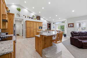 Kitchen with a breakfast bar area, a spacious island, open floor plan, recessed lighting, and light stone countertops