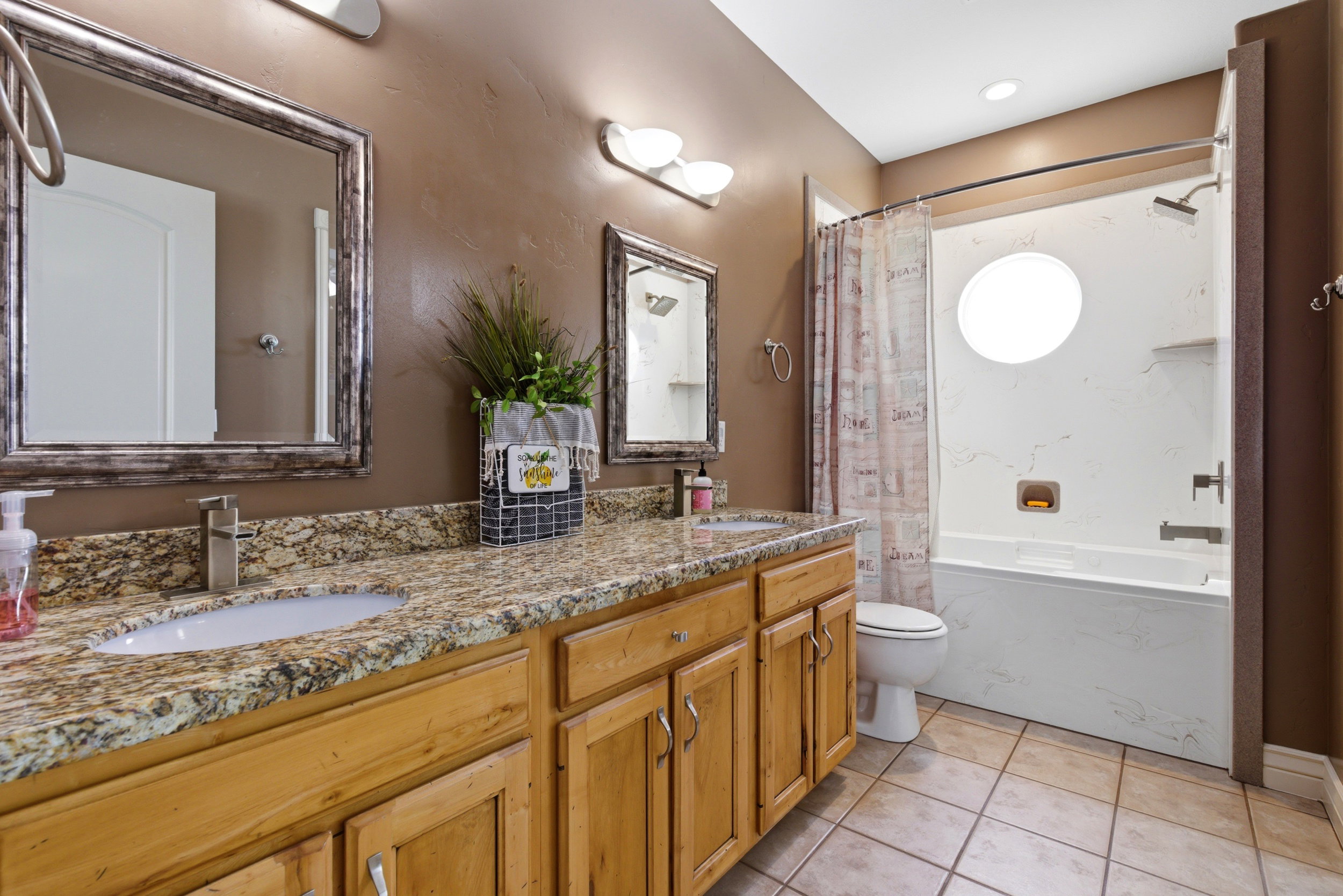 Bathroom featuring double vanity, a combined bath / shower with marble appearance, and light tile patterned floors