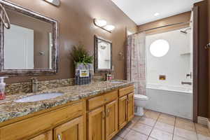 Bathroom featuring double vanity, a combined bath / shower with marble appearance, and light tile patterned floors