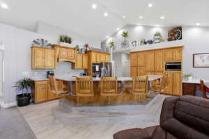 Kitchen with a breakfast bar area, a kitchen island with sink, light stone countertops, open floor plan, and a high ceiling