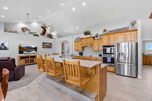 Kitchen with a large island, a kitchen bar, open floor plan, stainless steel appliances, and light wood finished floors