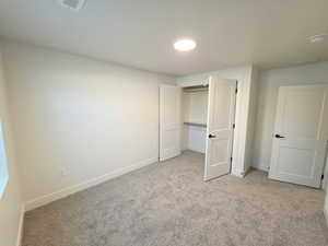 Unfurnished bedroom featuring light carpet and a closet