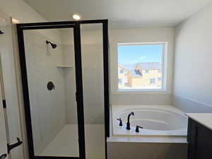 Bathroom featuring vanity, a marble finish shower, and a bath