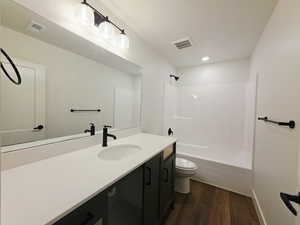 Bathroom with vanity, dark wood-type flooring, shower / washtub combination, and recessed lighting