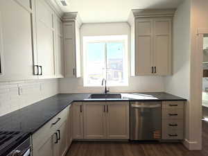Kitchen with dishwasher, dark wood finished floors, backsplash, and gray cabinetry