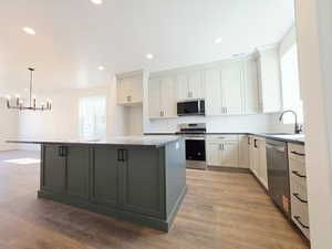 Dual tone kitchen with two tone cabinetry, a kitchen island, stainless steel appliances, plenty of natural light, and light wood-type flooring