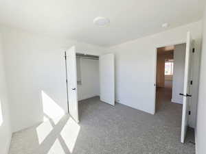 Unfurnished bedroom with light carpet and a closet