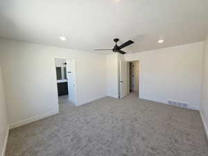 Unfurnished bedroom featuring recessed lighting, light carpet, ceiling fan, ensuite bath, and a textured ceiling