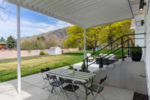 View of patio / terrace with outdoor dining area, a mountain view, and a storage shed