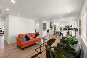 Living area with light wood finished floors and recessed lighting
