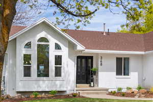 View of front of home featuring brick siding, a shingled roof, and covered porch