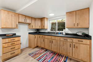 Kitchen featuring dark countertops, light wood-style floors, and light wood finish cabinets