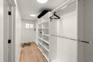 Walk in closet with light wood-style floors