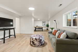 Living area with light wood-style floors and healthy amount of natural light