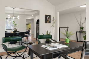 Office space featuring light wood finished floors, hanging lights, ornamental molding, and a tray ceiling