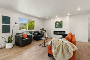 Living area with light wood-type flooring, a fireplace, recessed lighting, and a textured ceiling